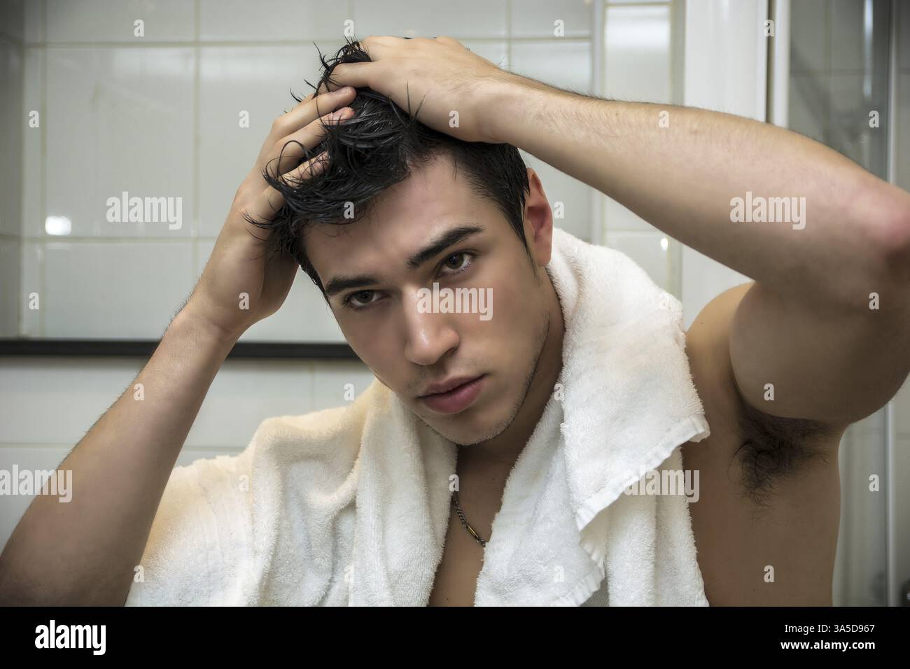 Gros plan magnifique jeune homme après ses douches avec White Towel sur ses épaules tenant sa tête Banque D'Images