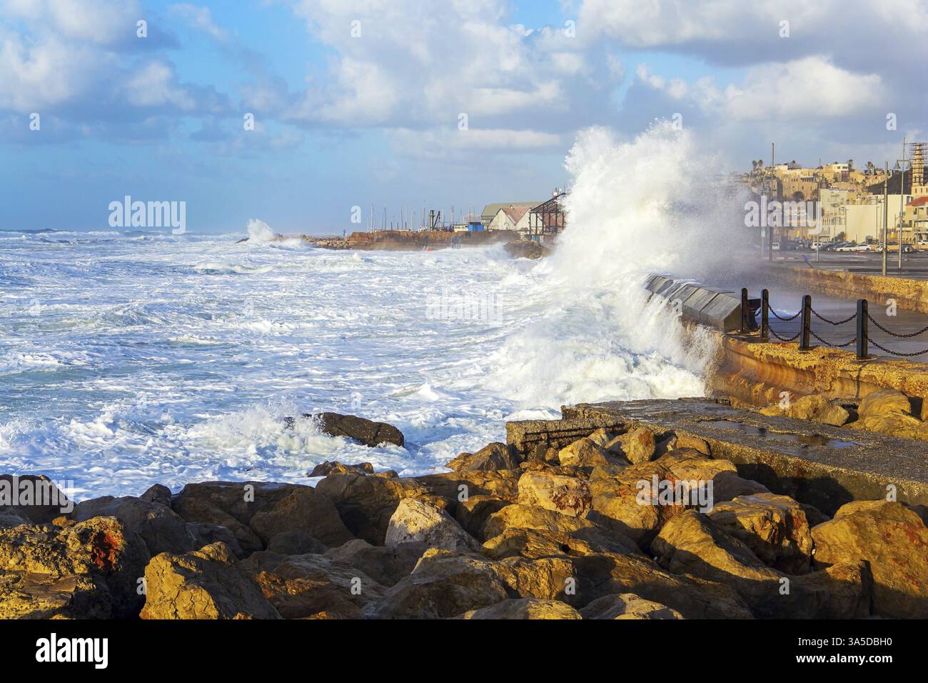 Des pierres énormes protègent la côte des énormes vagues de tempête. La puissante planche à voile d'hiver s'enferme avec de la mousse blanche à la neige. Remblai à tel Aviv. Coucher de soleil. Ensoleillé avec vent Banque D'Images