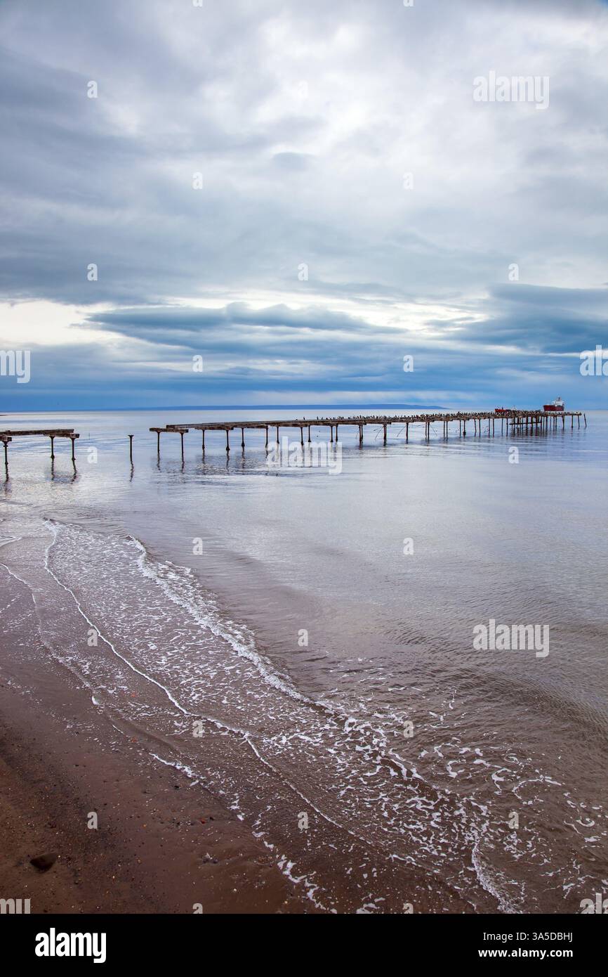 Jetée de l'océan en ruines à Punta Arenas. Détroit de Magellan. Amérique du Sud. La célèbre Tierra del Fuego est visible à l'horizon. Le ciel est couvert de h Banque D'Images