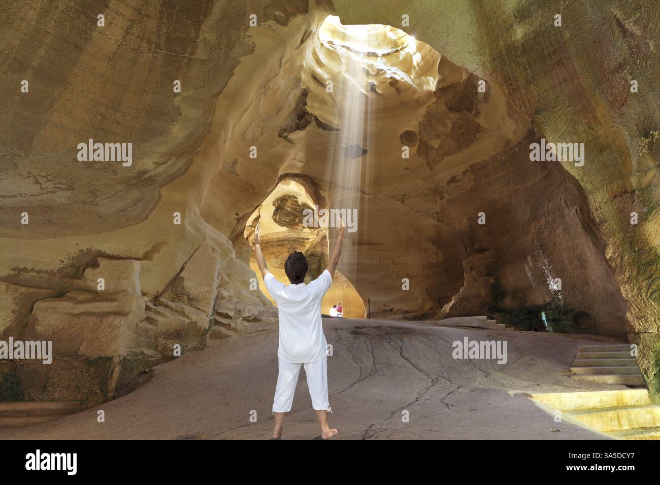Cours de yoga dans la grotte Beit Guvrin. Femme en blanc a accueilli rayon de soleil. Israël Banque D'Images