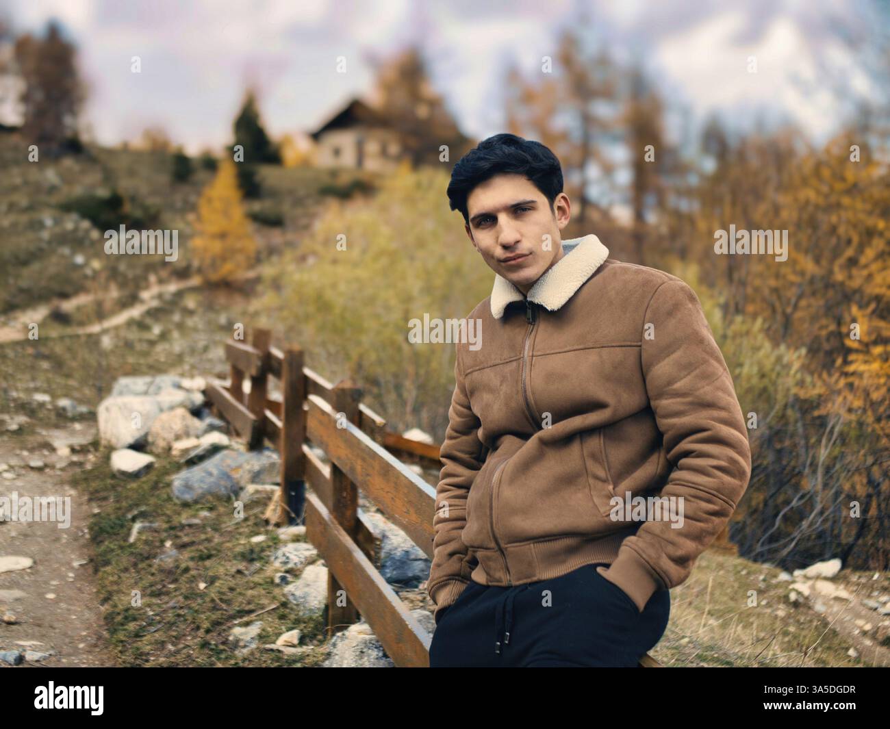 Jeune homme attrayant dans les montagnes en automne ou en hiver, temps froid, portant une veste en daim, regardant l'appareil photo Banque D'Images