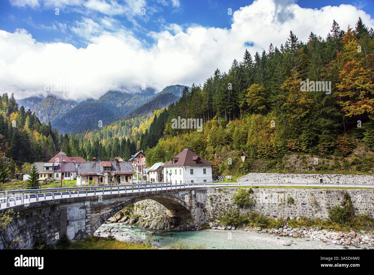 Pont et village sur un ruisseau de montagne peu profond. Voyage en Slovénie. Couleurs automnales des montagnes et des forêts. Les Alpes juliennes Banque D'Images