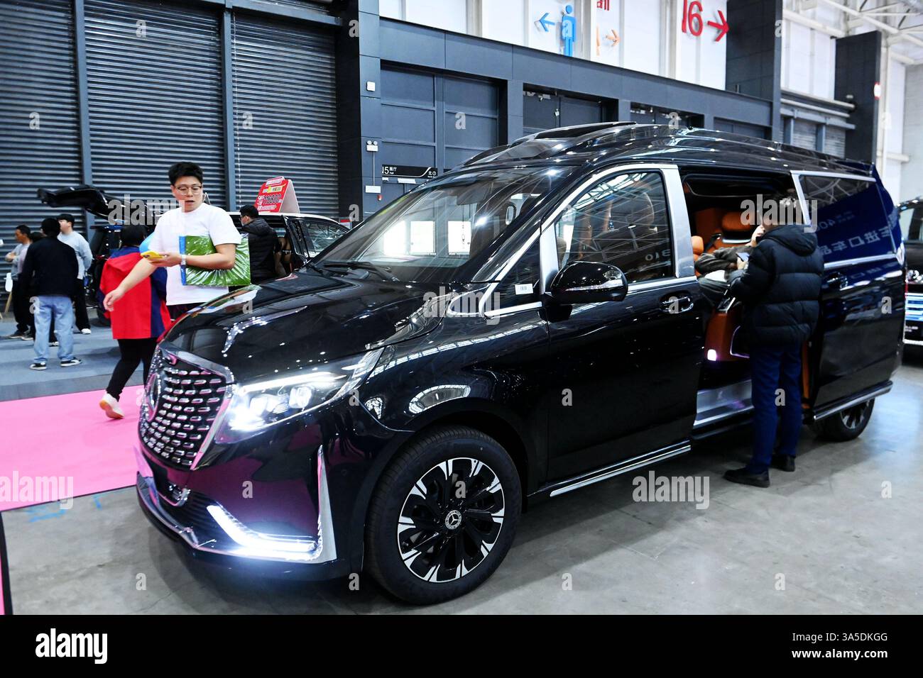 Les visiteurs regardent les véhicules exposés à Qingdao, dans la province du Shandong, en Chine, le 22 mars 2025. Banque D'Images