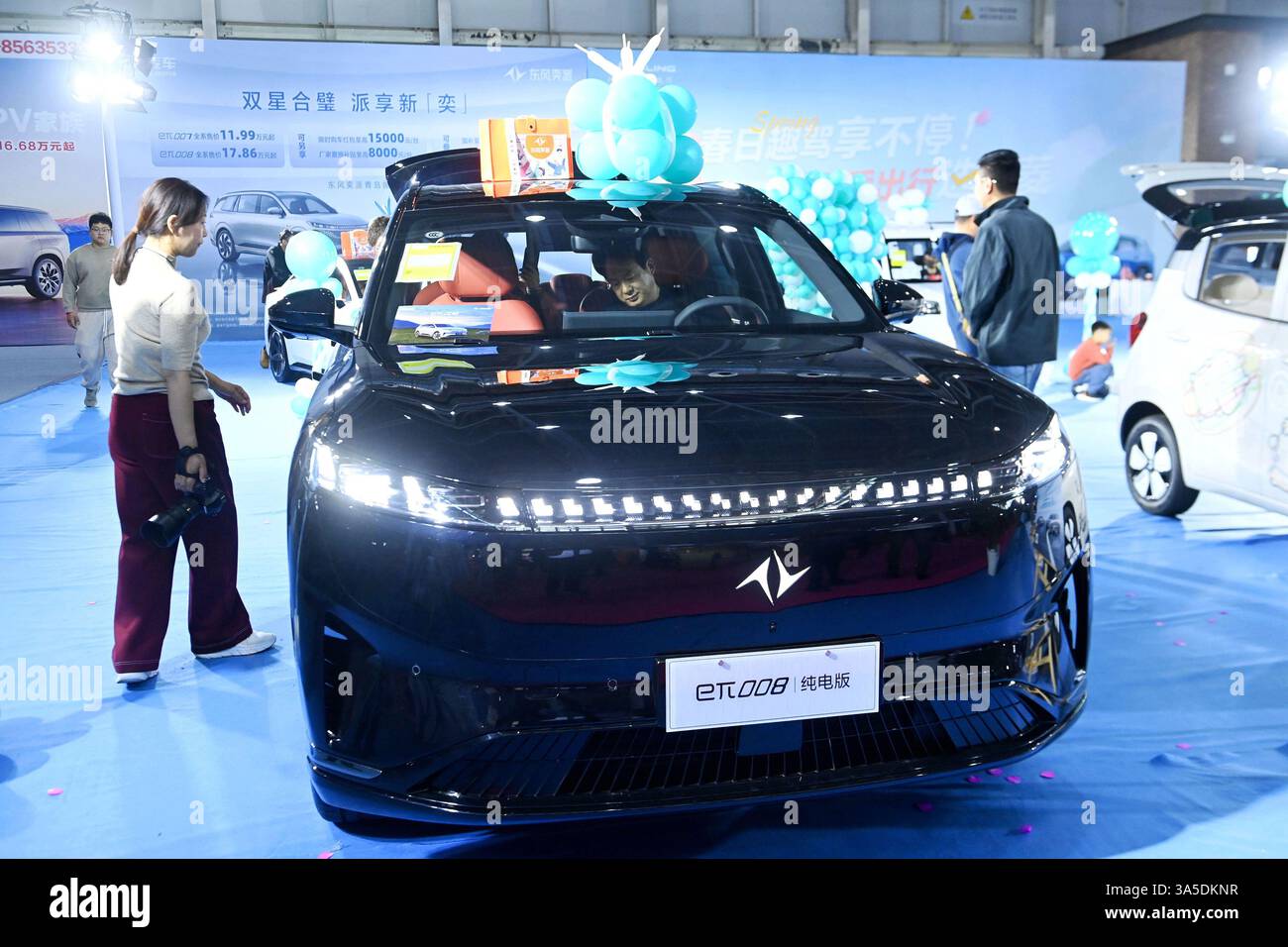 Les visiteurs regardent les véhicules exposés à Qingdao, dans la province du Shandong, en Chine, le 22 mars 2025. Banque D'Images