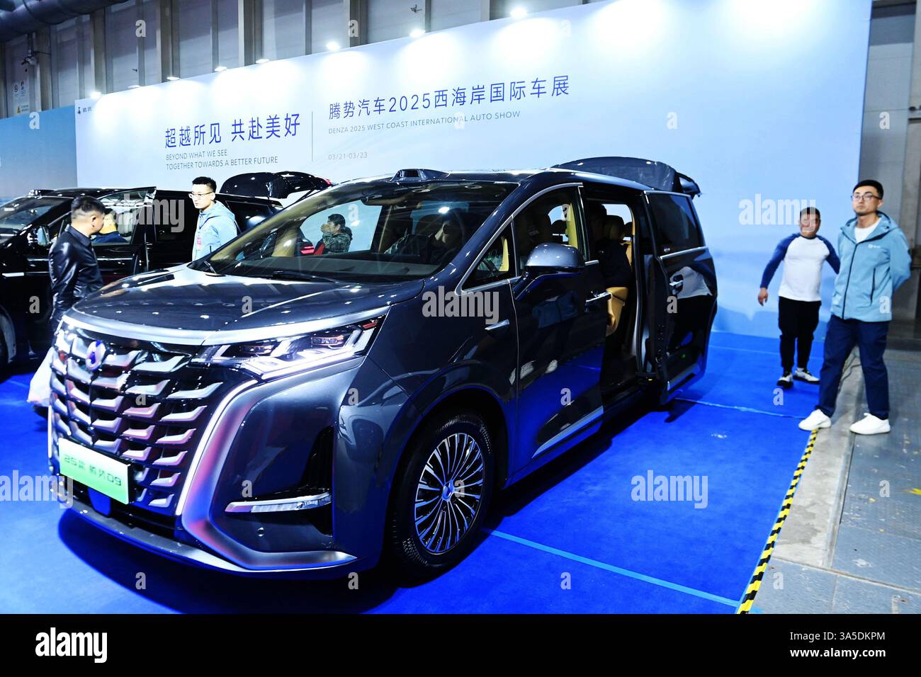 Les visiteurs regardent les véhicules exposés à Qingdao, dans la province du Shandong, en Chine, le 22 mars 2025. Banque D'Images