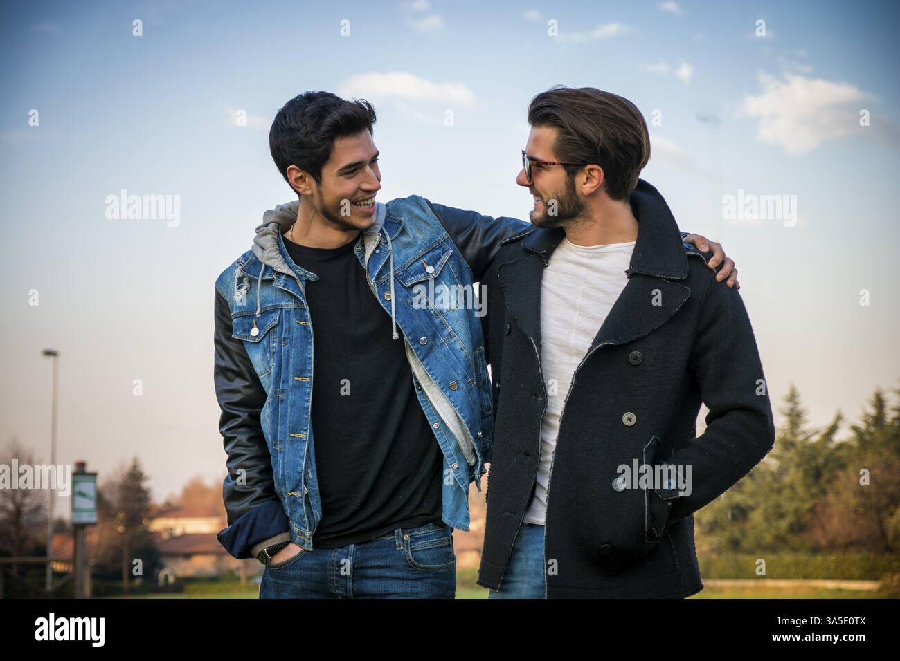 Deux beaux jeunes hommes à la mode décontractée, 2 amis, dans un parc urbain de marcher et de parler ensemble Banque D'Images
