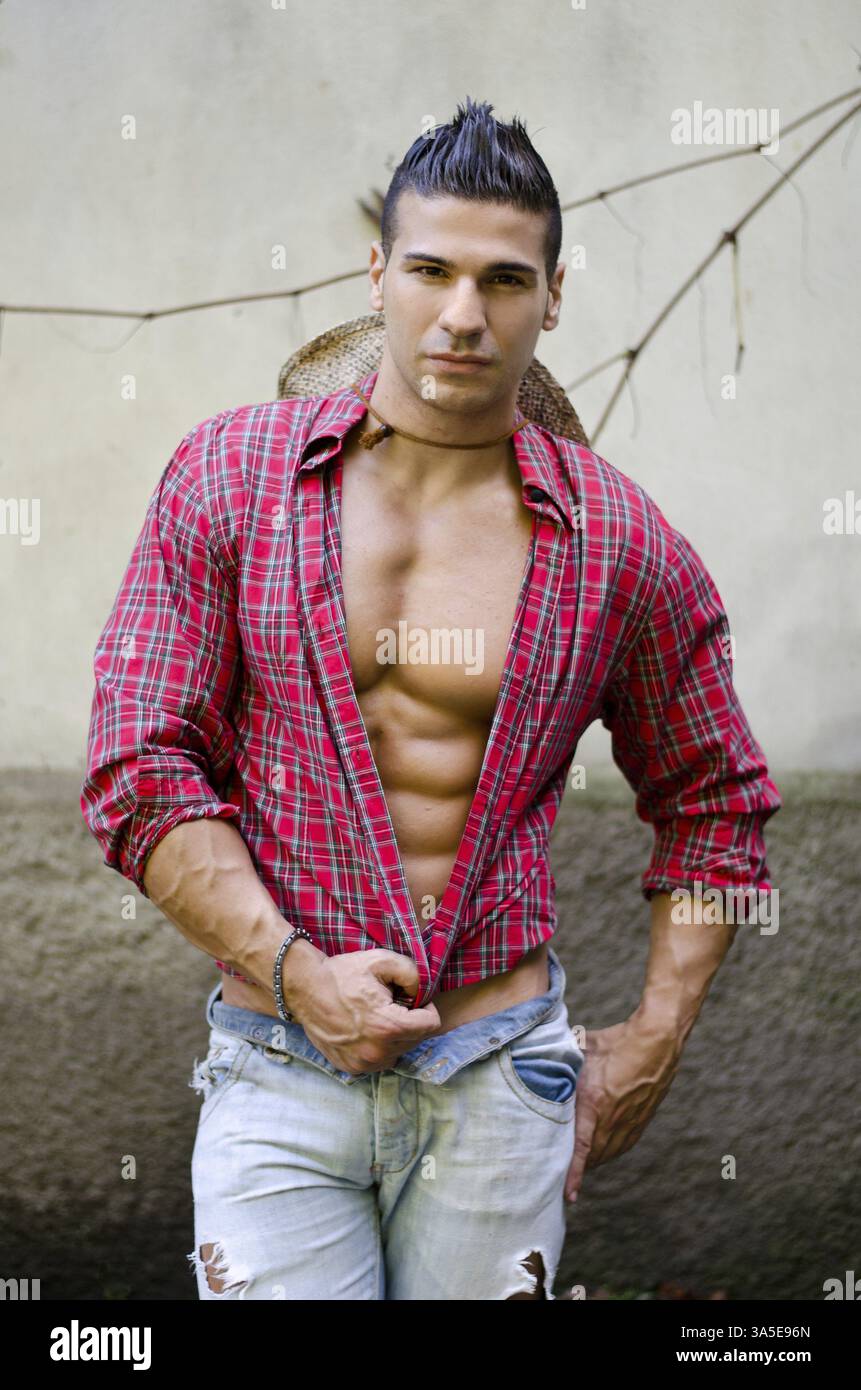 Beau jeune homme musclé, avec chemise, jeans et chapeau de paille à l'extérieur Banque D'Images