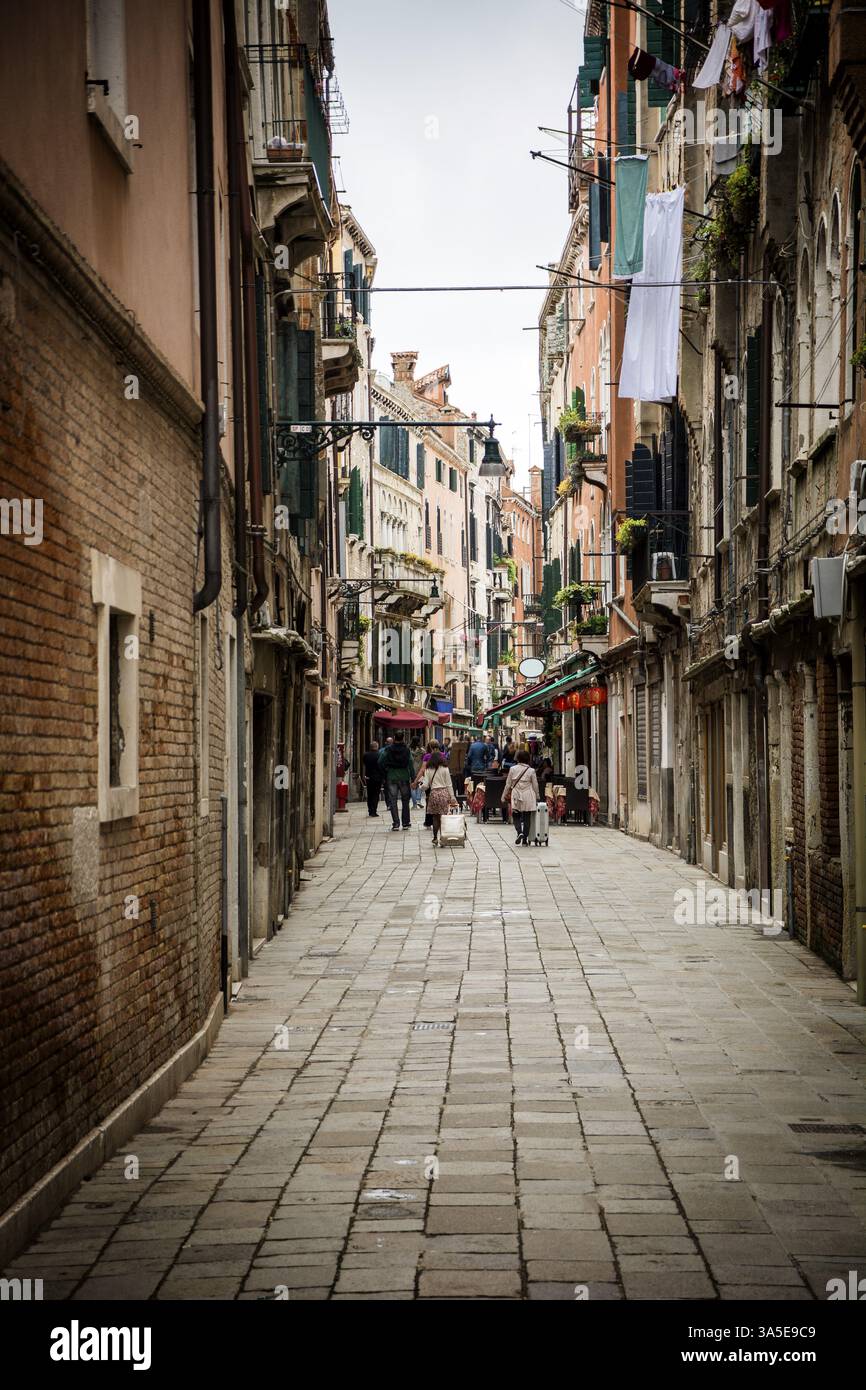 Une rue étroite avec des gens marchant dessus. Photo de personnes se promenant dans une charmante rue étroite de Venise, Italie, Europe Banque D'Images
