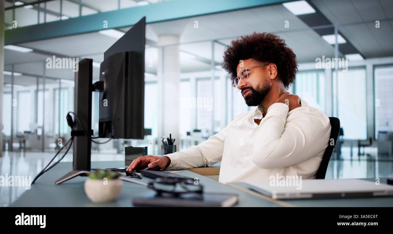 Homme d'affaires afro-américain professionnel avec mal de cou derrière l'ordinateur de bureau. Banque D'Images