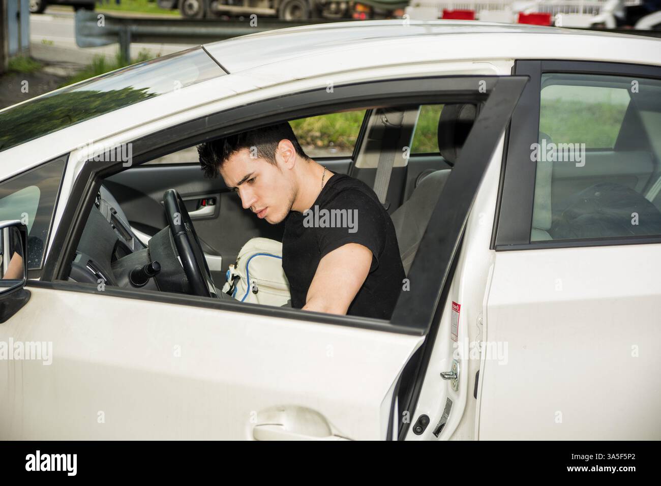 Jeune homme séduisant sortir de voiture blanche, ouvrant la porte Banque D'Images