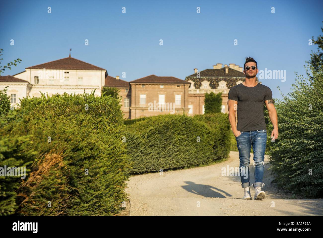 Bel homme musclé avec tatouage posant dans le jardin de luxe européen au palais royal Venaria Reale près de Turin, Italie, Europe Banque D'Images
