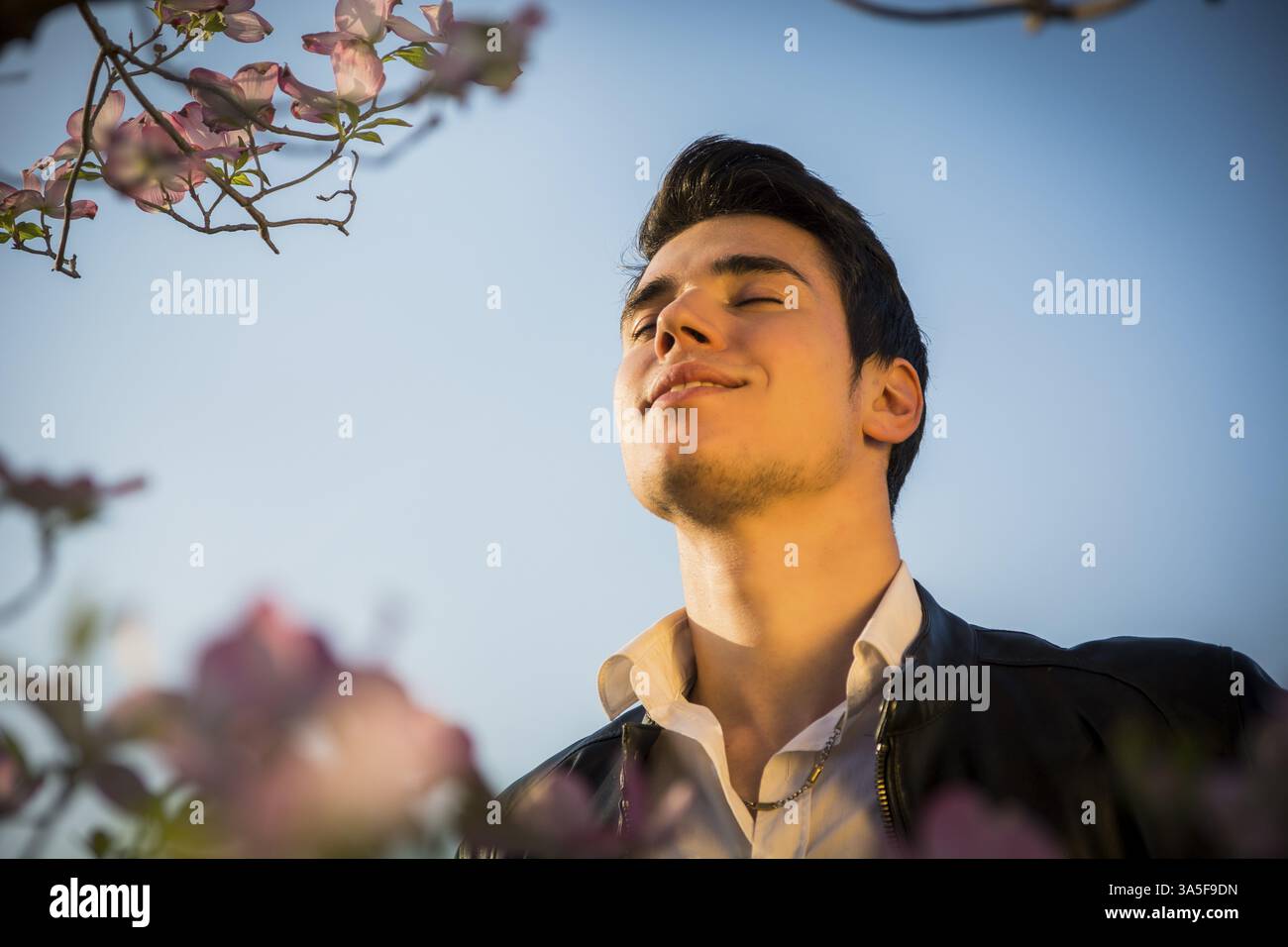 Beau modèle masculin à couuntryside, parmi les fleurs, appréciant la nature Banque D'Images