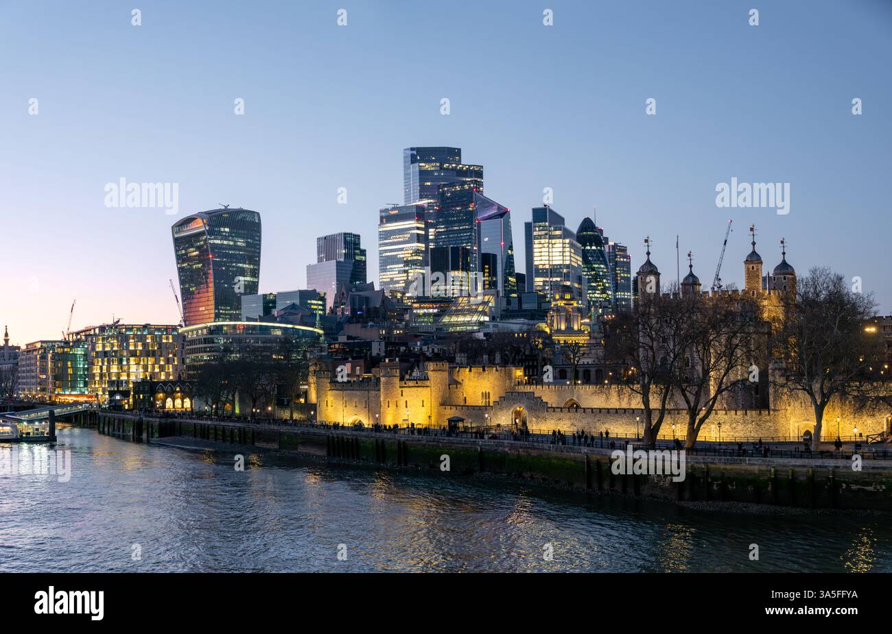 La skyline du district financier de la City de Londres et la forteresse illuminée du Tower de Londres le long de la Tamise au crépuscule, Angleterre, Royaume-Uni Banque D'Images