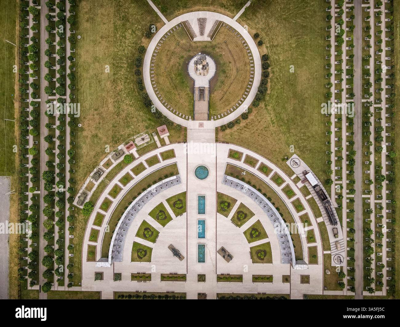 Vue aérienne du parc mémorial de Magas, avec des allées symétriques, des fontaines, de la verdure et la tour Ingouch historique dans un environnement serein. Banque D'Images