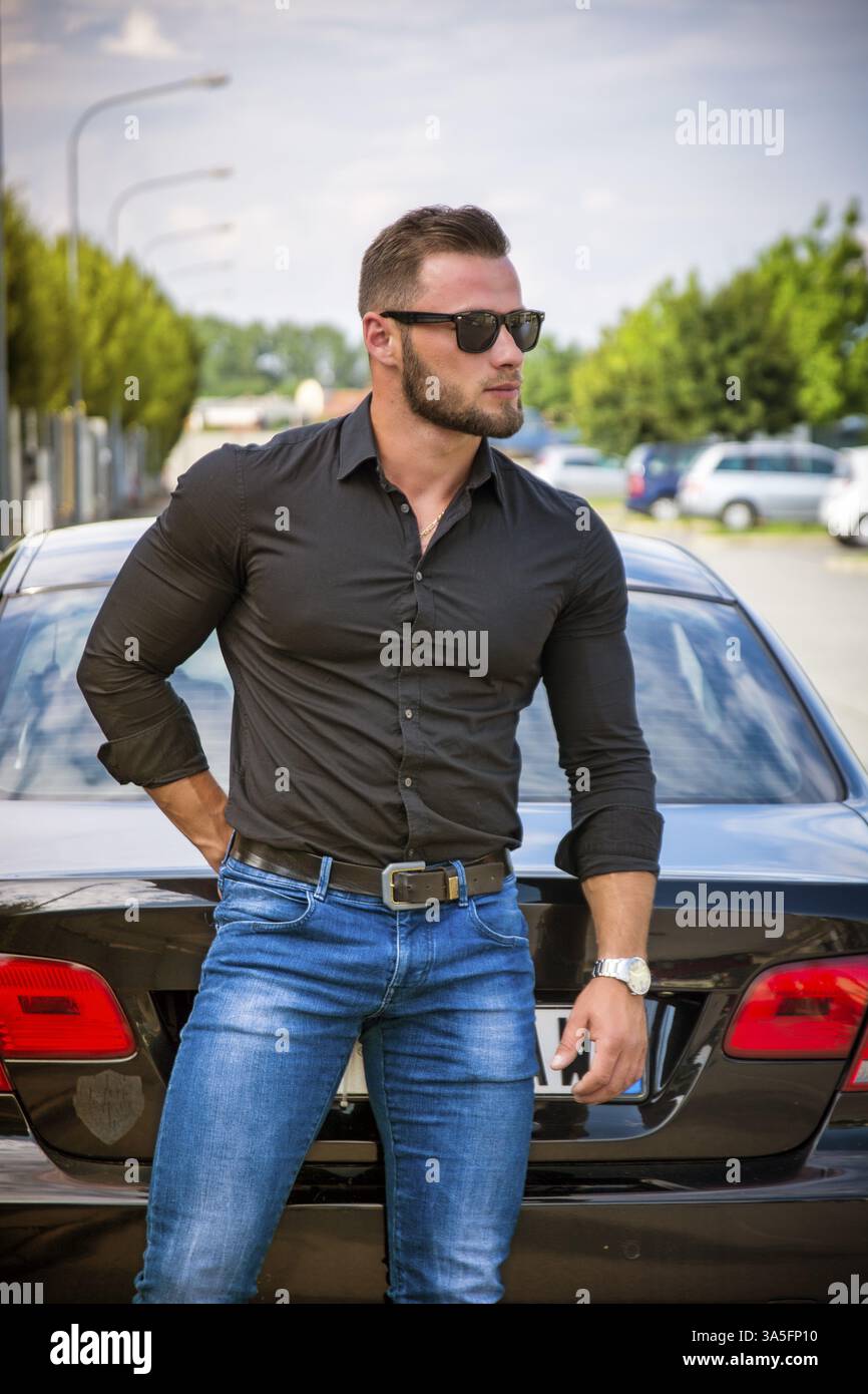 Portrait de jeune homme barbu à lunettes s'appuyant sur son nouveau style extérieur voiture poli Banque D'Images