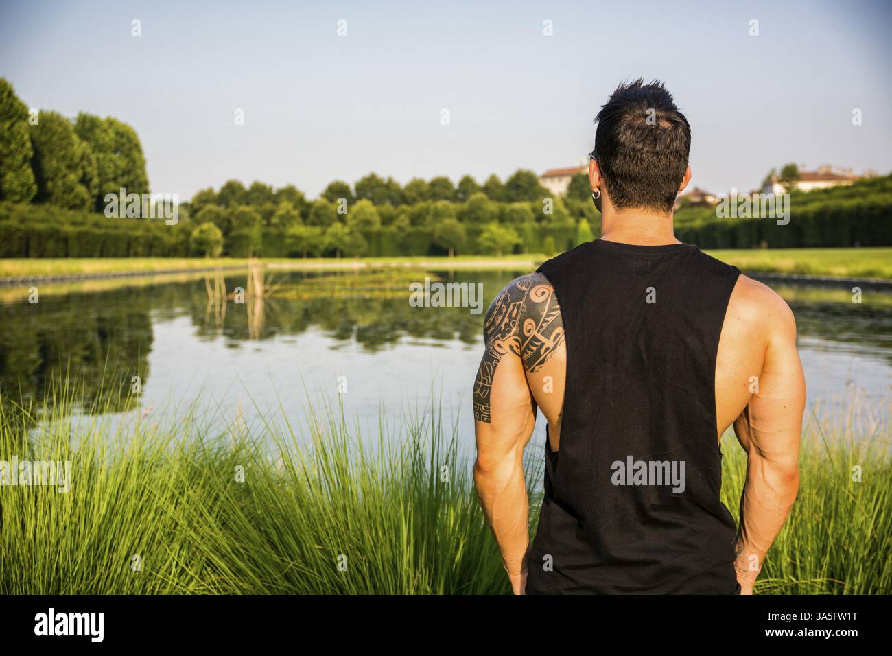 Dos d'homme musclé avec tatouage posant dans le jardin de luxe européen au palais royal Venaria Reale près de Turin, Italie, Europe Banque D'Images