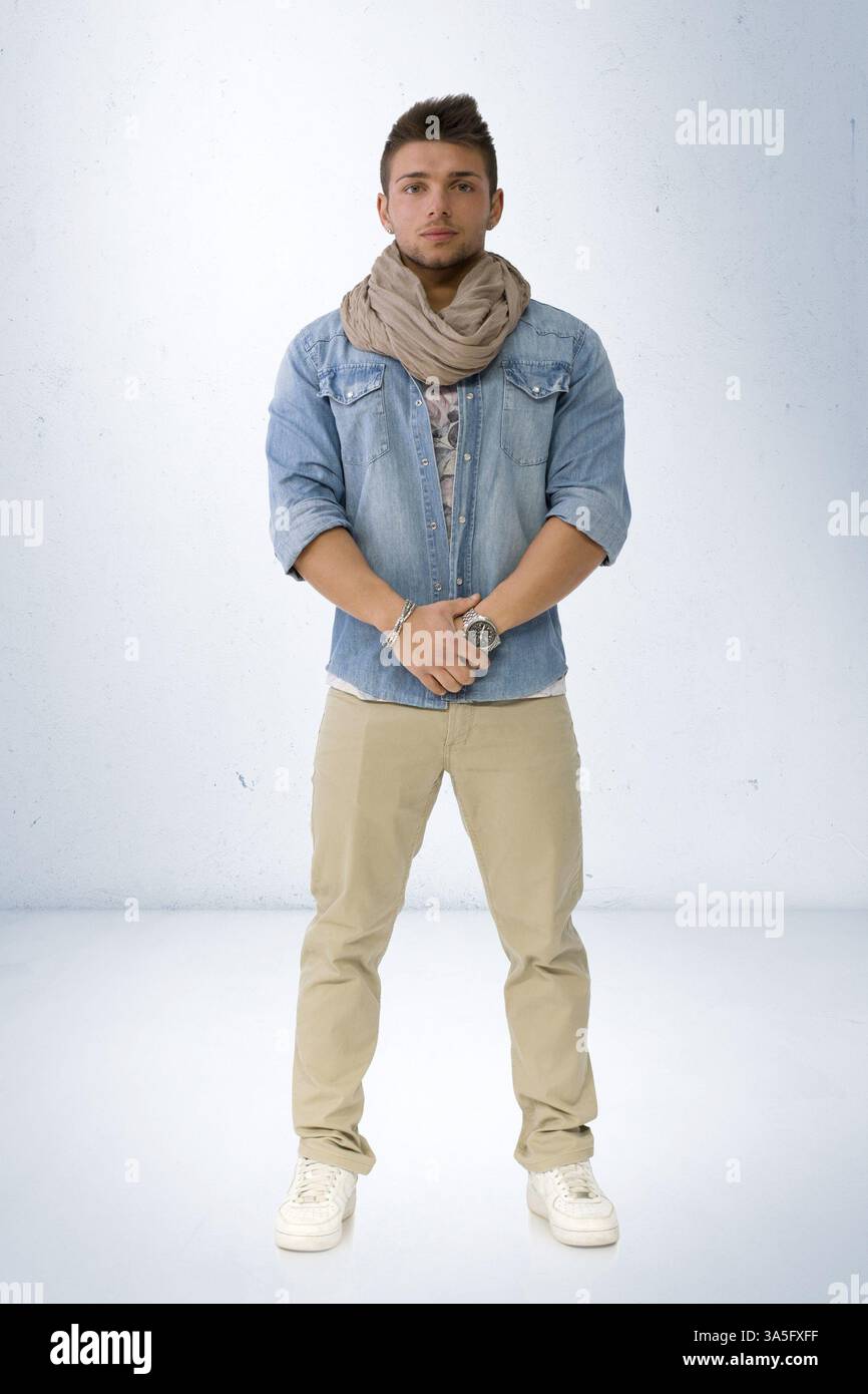 Beau jeune homme debout avec chemise en denim et écharpe, pleine longueur du corps Banque D'Images