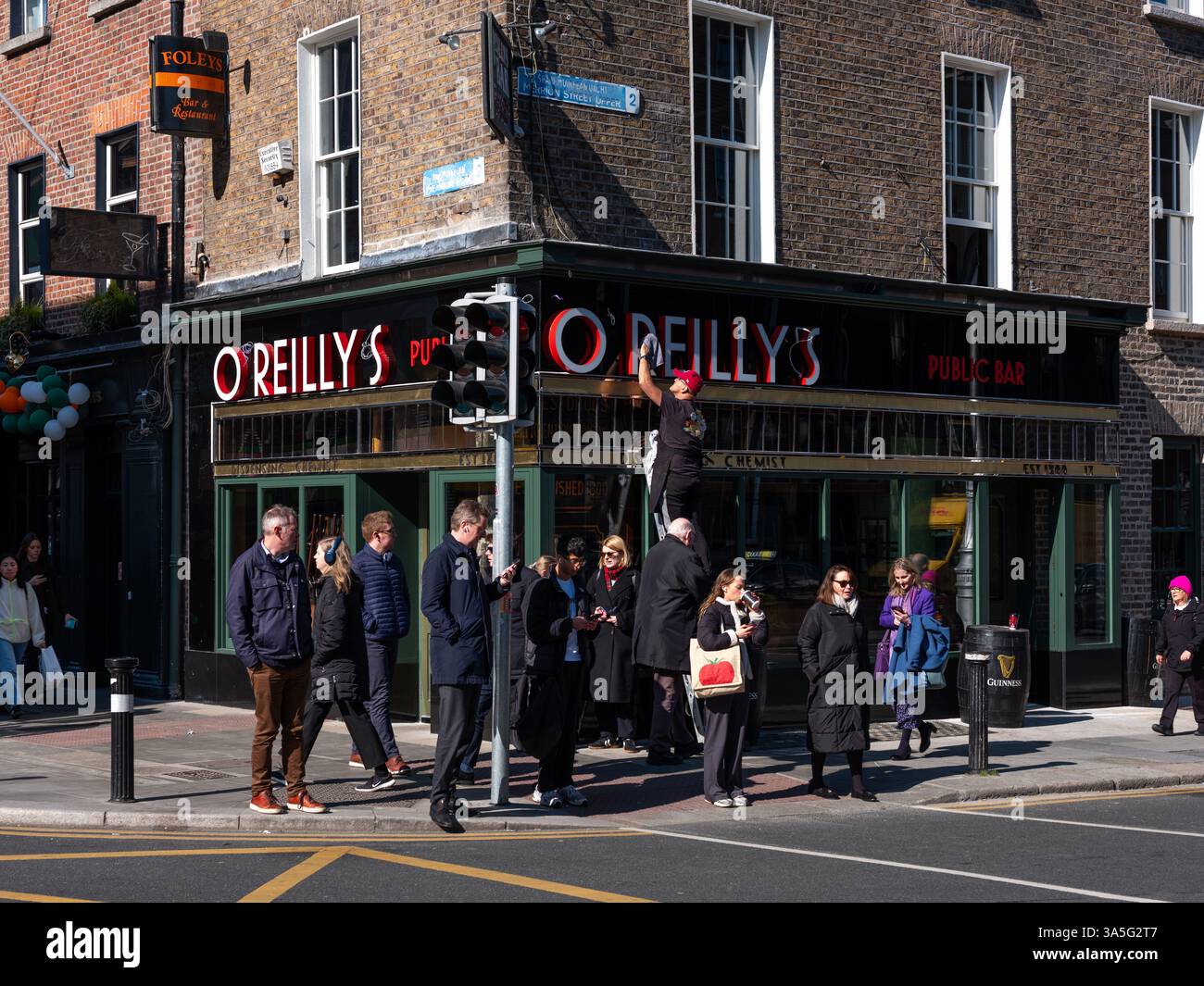 Un homme nettoie la façade de O'Reilly's sur Merrion Row à Dublin, Irlande. Banque D'Images