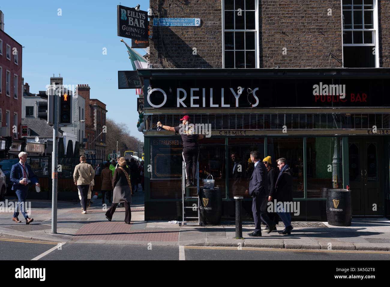 Un homme nettoie la façade de O'Reilly's sur Merrion Row à Dublin, Irlande. Banque D'Images