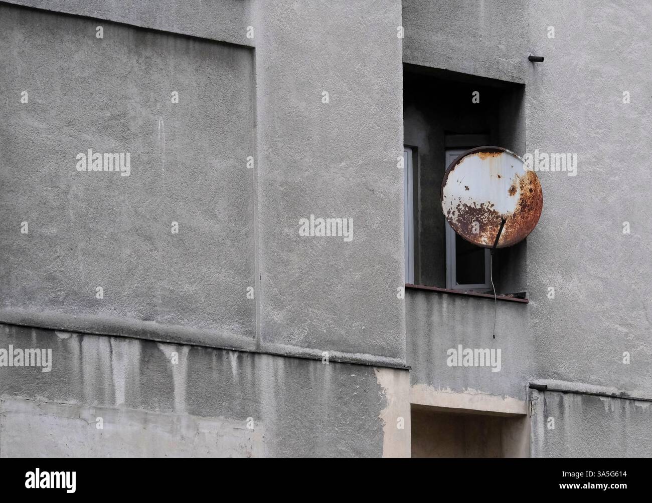 Antenne parabolique rouillée à la fenêtre d'un bâtiment gris Banque D'Images