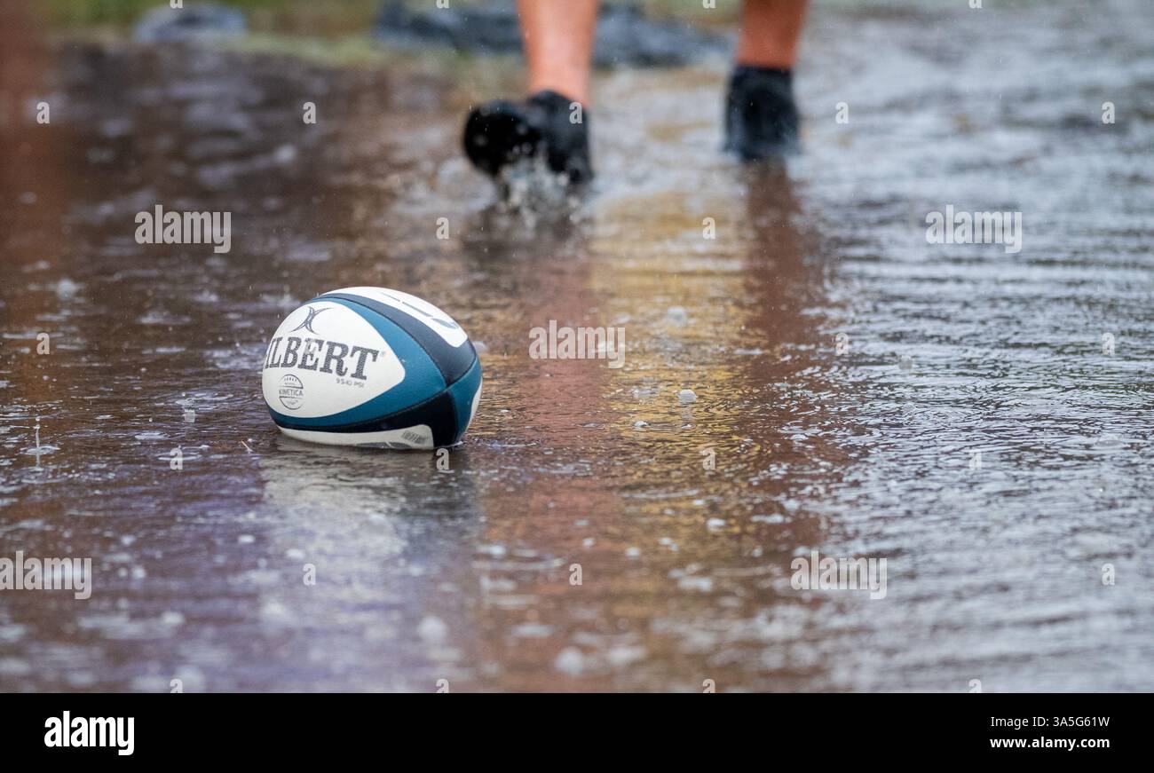 Récupérer une balle de rugby d'une flaque pendant un match amateur de rugby à XV pour hommes après une pluie battante. Banque D'Images