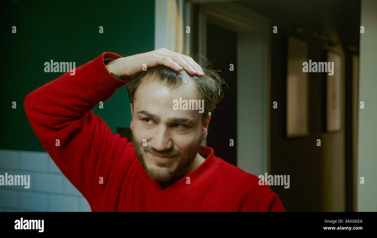 Homme appliquant le sérum de perte de cheveux semblant stressé inquiet de l'amincissement des cheveux et la santé des cheveux en utilisant le traitement dans la routine quotidienne de toilettage Banque D'Images