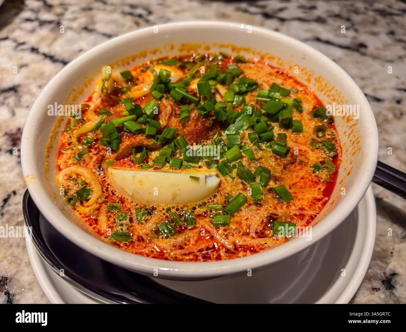 Délicieux gros plan de Penang Assam Laksa. Soupe de poisson aigre avec nouilles, garnie d'oignons de printemps, d'oeufs tranchés et de légumes. Banque D'Images