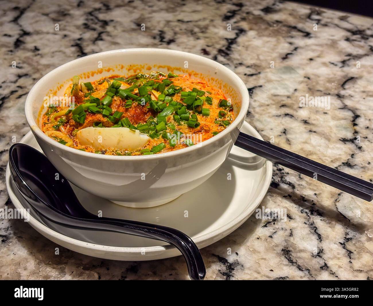 Penang Assam Laksa saveurs authentiques avec des nouilles, du poisson dans une soupe aigre, garni d'oignons verts, d'oeufs, de légumes dans un bol. Banque D'Images