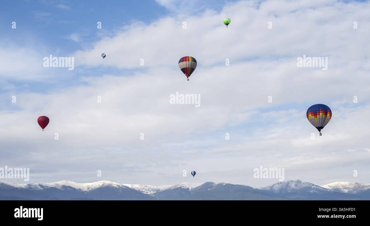 Ballons multicolores dans le bleu ciel nuageux Banque D'Images
