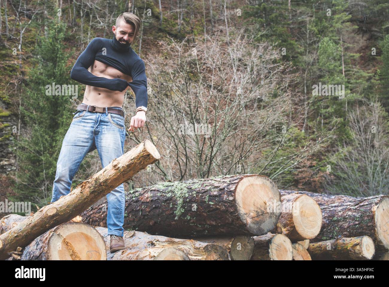 Jeunes hommes sur des bûches dans la forêt. Les hommes s'habillent Banque D'Images