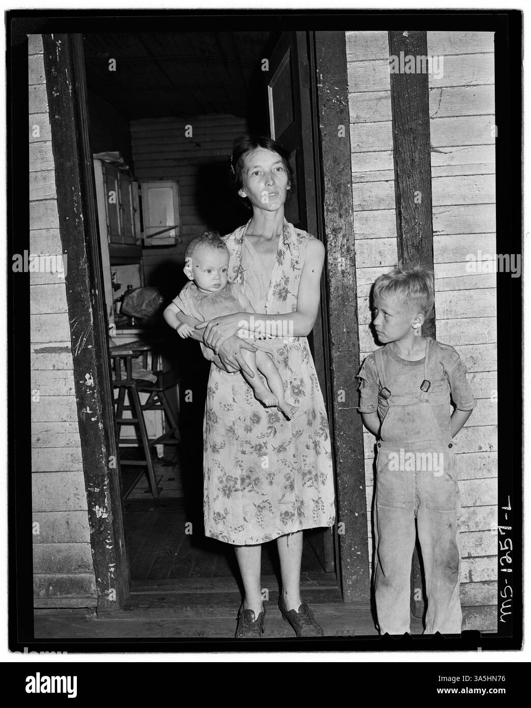 MRS Walter Rose, avec ses deux enfants, se tient à l'entrée de leur modeste maison de trois pièces. Leur bébé, nourri de lait en poudre, a récemment rendu visite au médecin de l’entreprise, illustrant les soins de santé et les conditions de vie dans une communauté minière. Banque D'Images