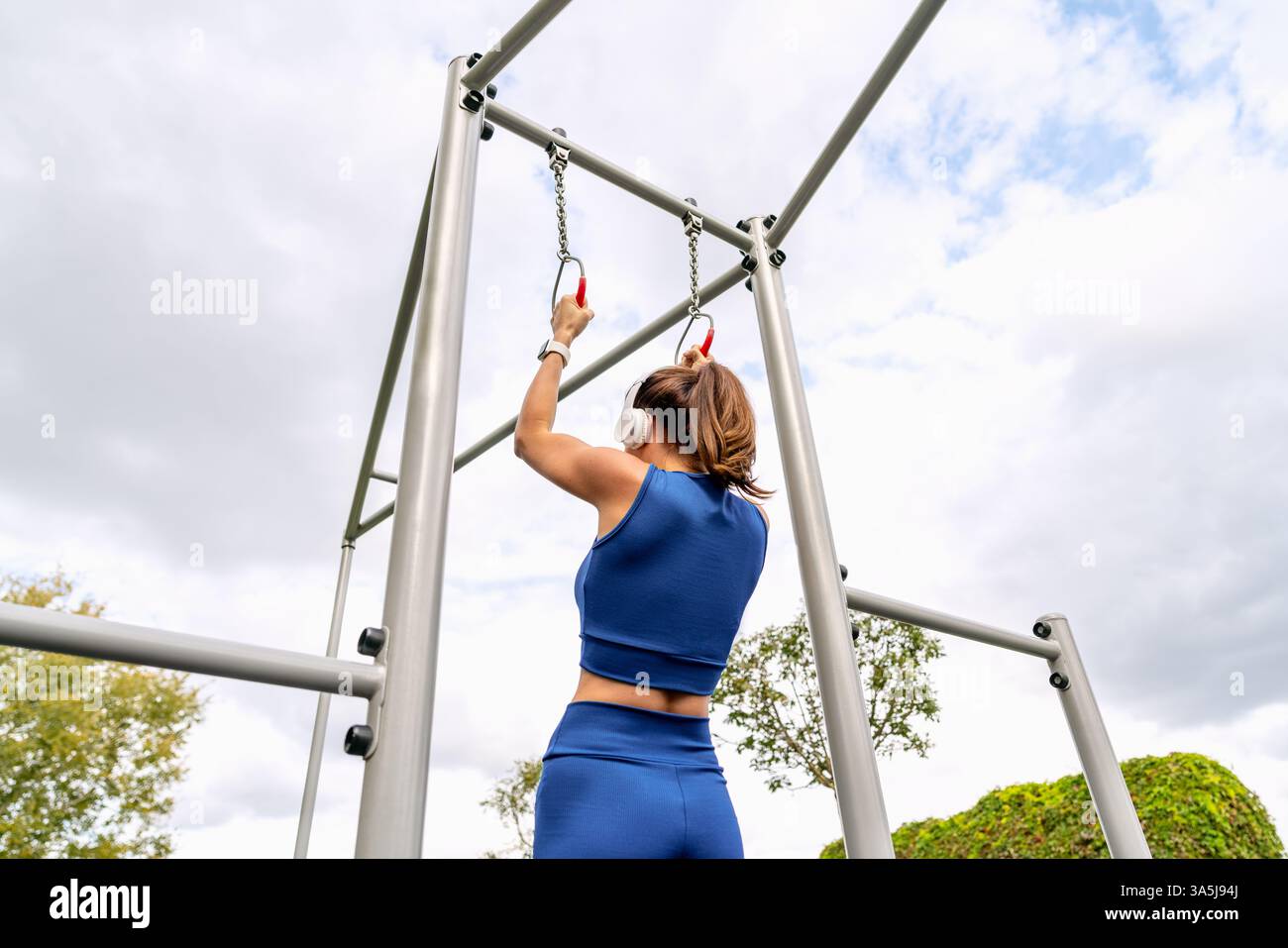 Vue arrière à angle bas d'une jeune femme athlétique tenant des anneaux de gymnastique dans un parc de fitness extérieur. Banque D'Images