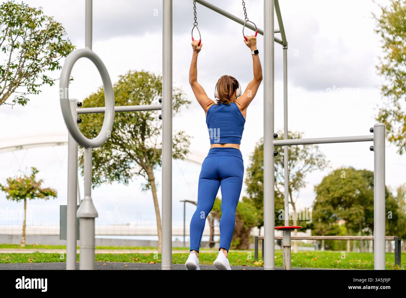 Vue arrière d'une jeune femme athlétique tenant des anneaux de gymnastique dans un parc de fitness extérieur Banque D'Images