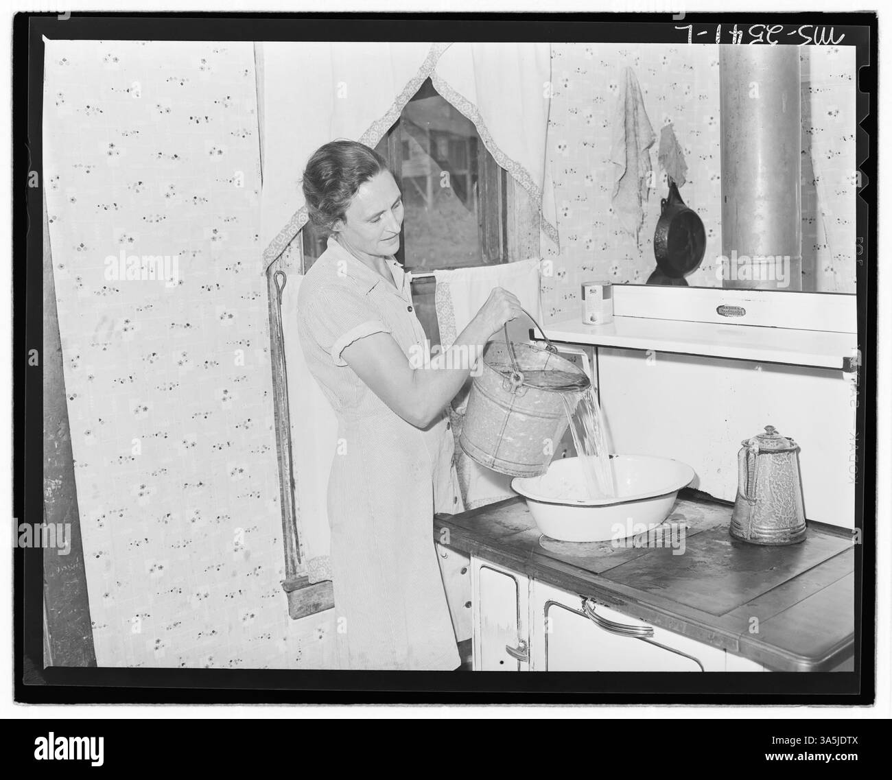 MRS Sergent chauffe l'eau pour le bain de son mari à la mine Clover Gap de P V & K Coal Company à Lejunior, dans le comté de Harlan, Kentucky, illustrant les responsabilités personnelles et domestiques dans les familles minières. Banque D'Images