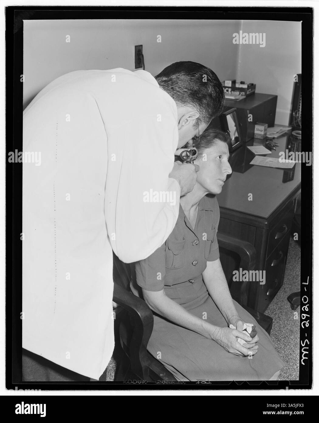 Un professionnel de la santé examine un patient avec un otoscope à la clinique de la U.S. Coal & Coke Company au service des travailleurs des mines américaines #30 & 31 à Lynch, Kentucky. Cela reflète les services de santé fournis aux mineurs et à leurs familles dans la région. Banque D'Images