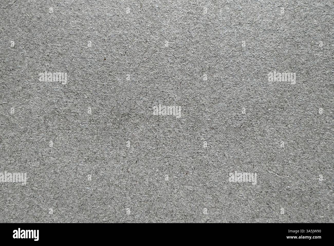 Texture de carton gris, gros plan. Surface neutre et rugueuse avec imperfections naturelles de grain visibles. Idéal pour les décors, l'emballage ou le projet de conception Banque D'Images