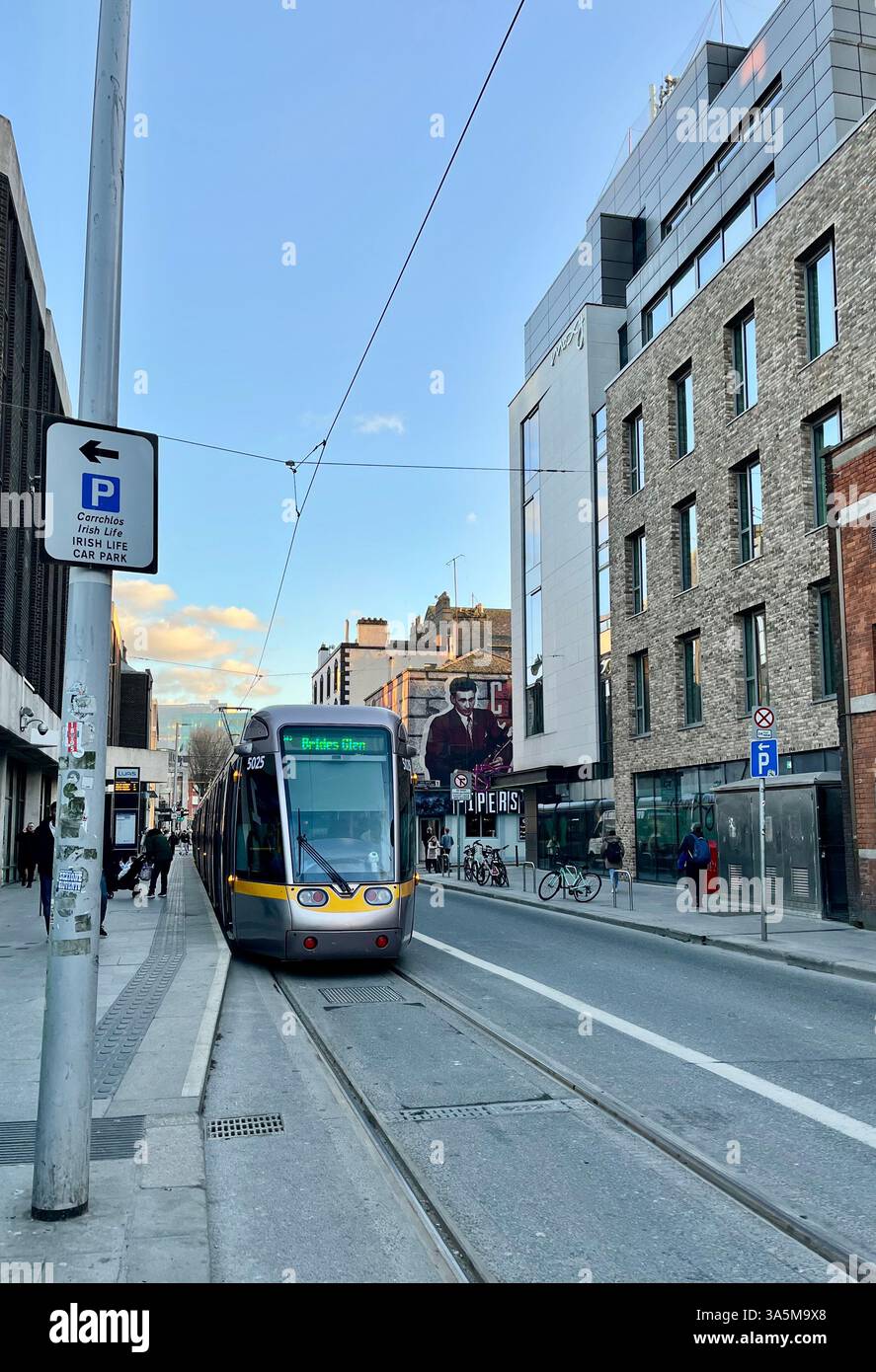 Un tramway moderne parcourt les rues de Dublin, en Irlande, sous un ciel bleu clair. - Image de stock capturée avec un smartphone