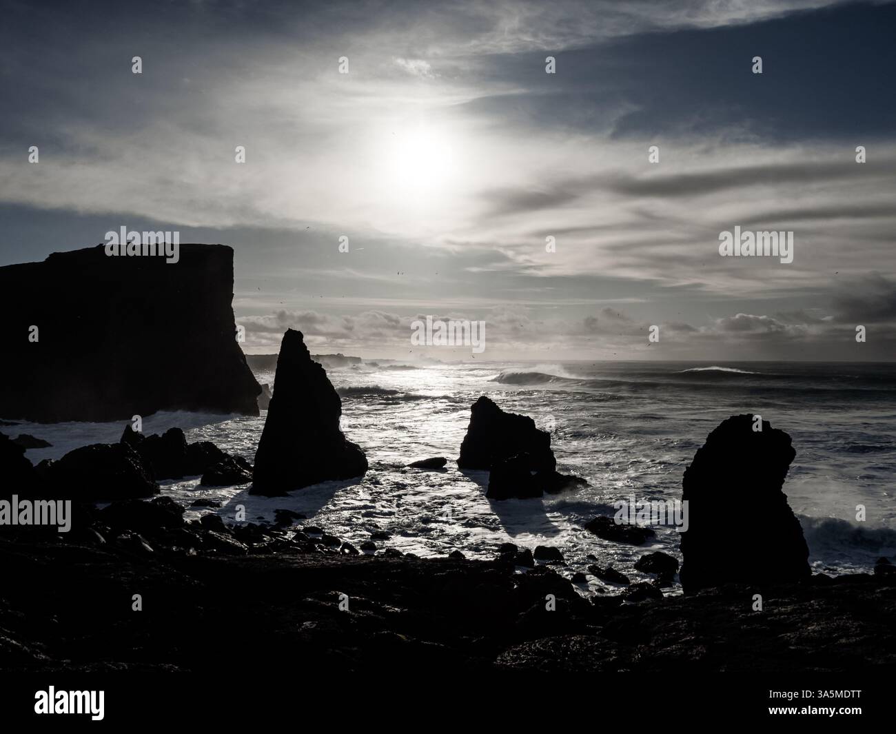 Coucher de soleil spectaculaire sur Valahnúkamöl, Islande. Des piles de mer déchiquetées s'élèvent de l'Atlantique turbulent tandis que le soleil projette de longues ombres, éclairant la puissance A. Banque D'Images