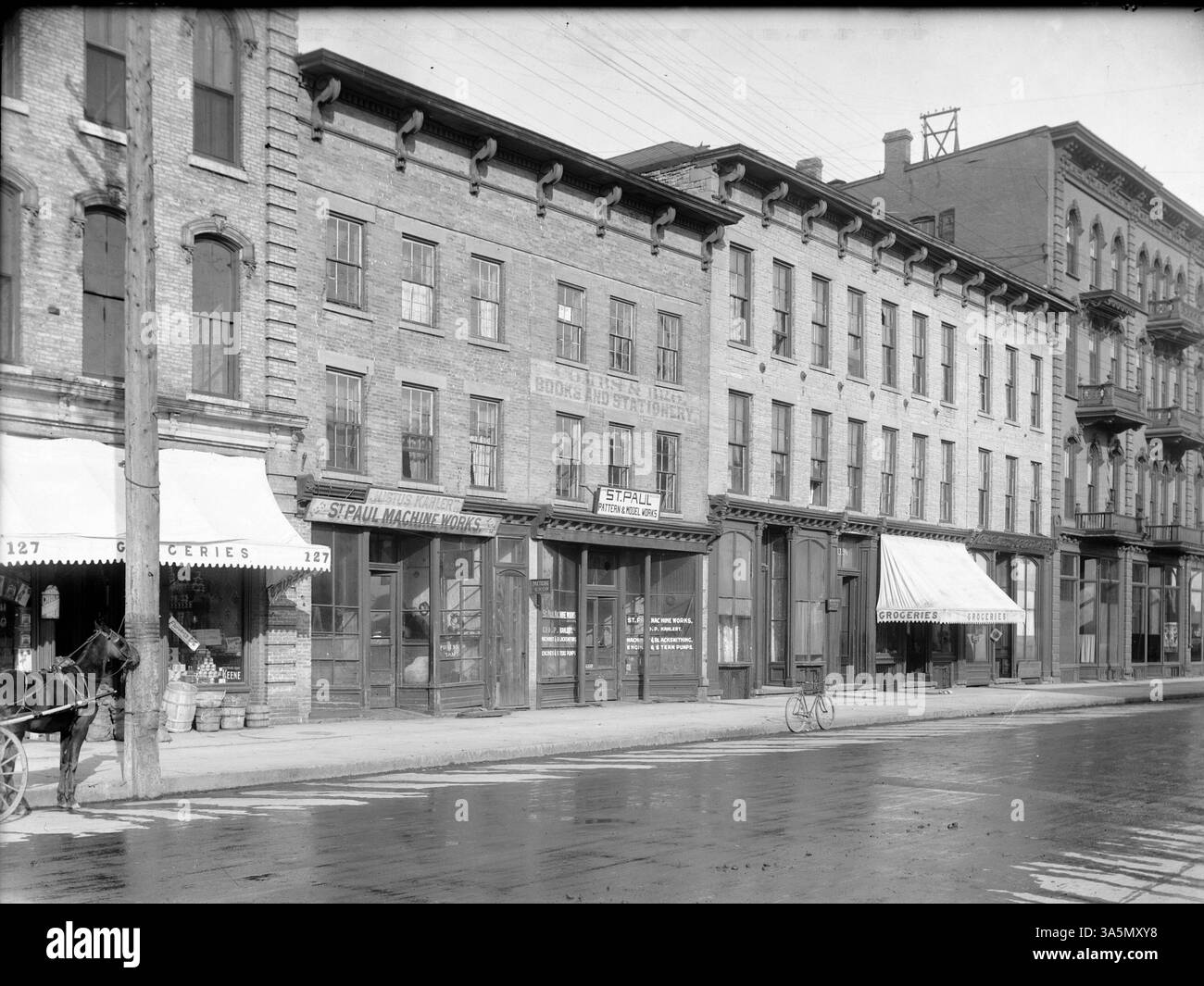 Cette image montre divers commerces sur Third Street près de Washington Street, y compris la Hennepin County Library, les travaux de Paul machine dans l'ancien bâtiment de la librairie Combs, et l'ancien Cheritree and Farwell Store. Le Metropolitan Hotel est visible à l'extrême droite. Banque D'Images
