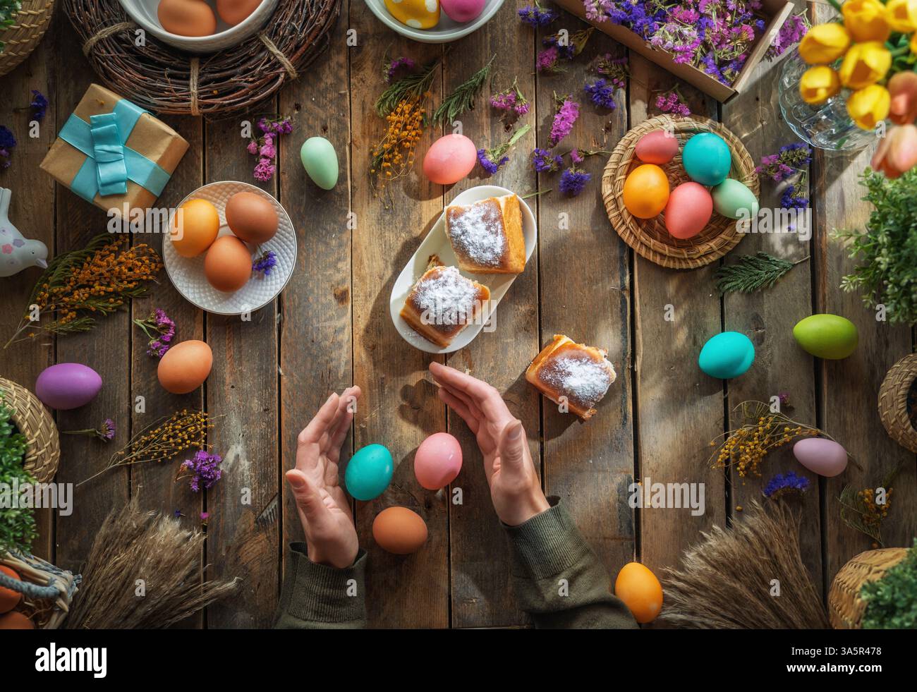 Fond de vacances de Pâques. Oeufs colorés et fleurs sur la table en bois. Vue de dessus Banque D'Images