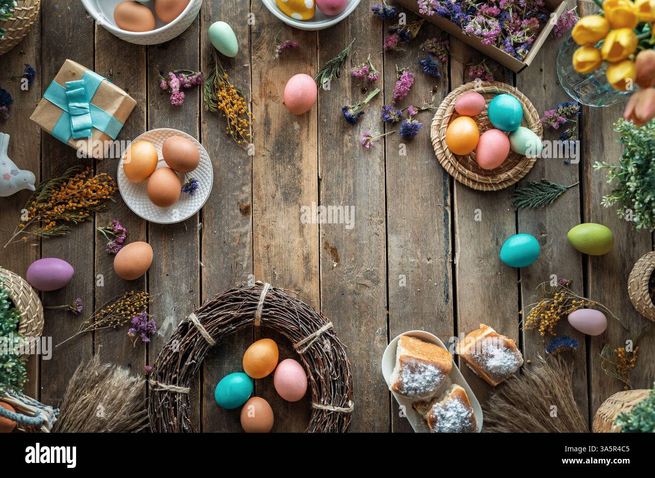 Fond de vacances de Pâques. Oeufs colorés et fleurs sur la table en bois. Vue de dessus Banque D'Images