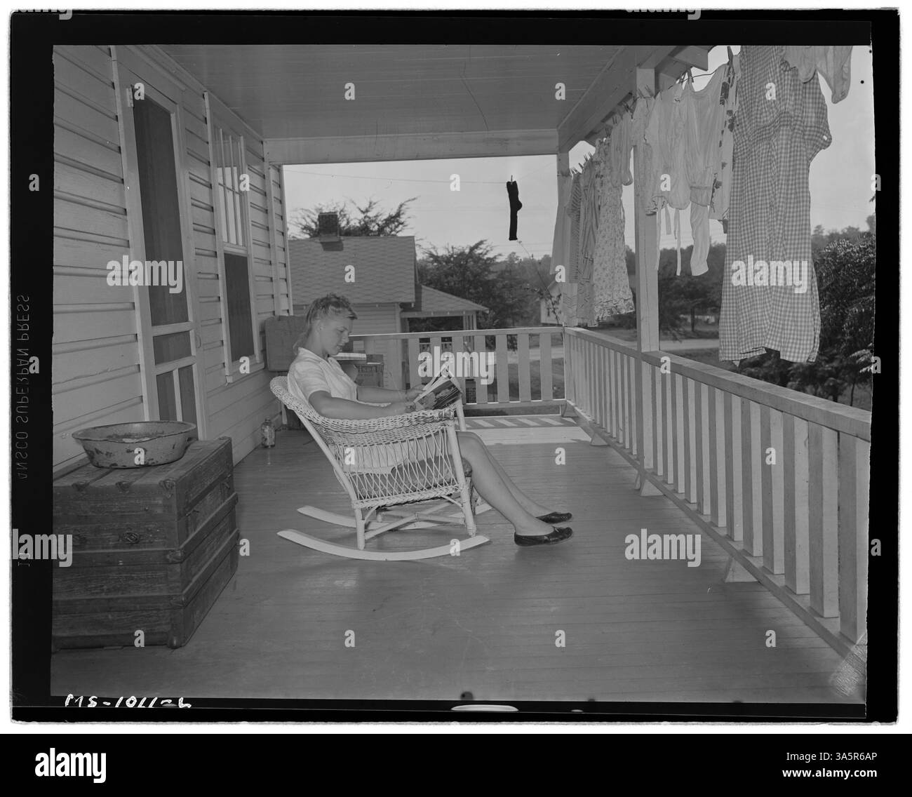 Betty Wilson, fille du mineur Rufus Wilson, est photographiée en train de lire sur le porche arrière de leur maison dans un projet de logement d'entreprise près de la mine Gorgas de l'Alabama Power Company dans le comté de Walker, en Alabama. La photo offre un aperçu de la vie des familles de mineurs de charbon de la région. Banque D'Images