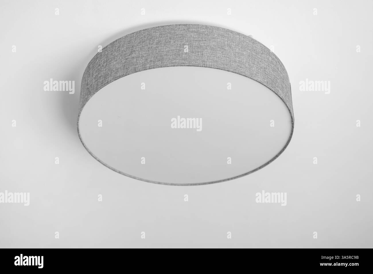 Plafonnier avec abat-jour à tambour peu profond avec diffuseur en coton gris dans un intérieur minimaliste élégant, mise au point sélective Banque D'Images