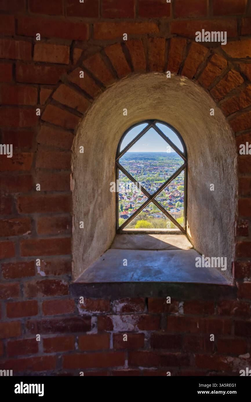 Vue sur le paysage urbain à travers une vieille fenêtre dans une tour de briques Banque D'Images