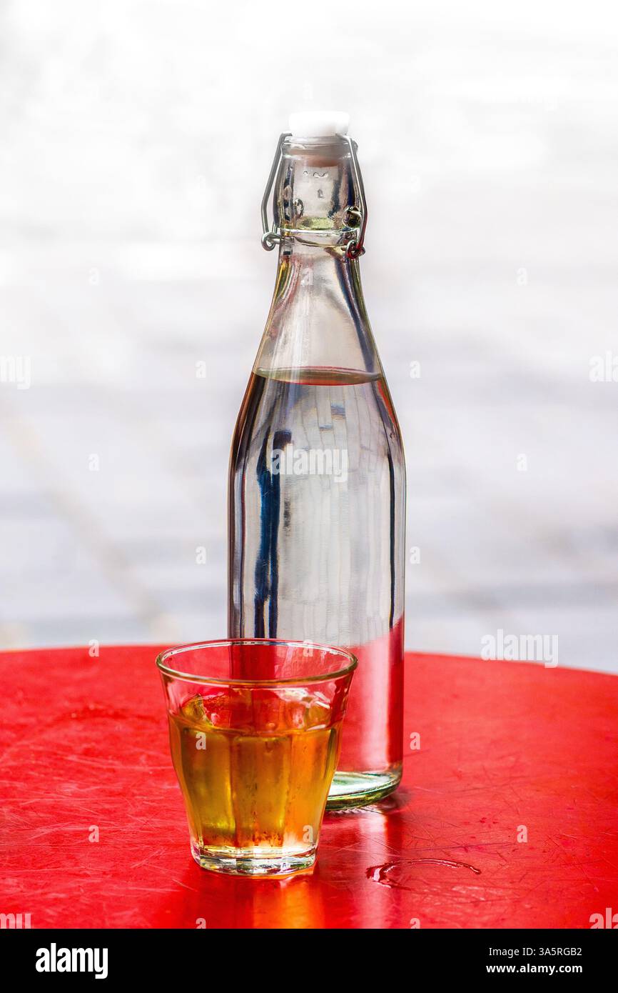 Bouteille d'eau et petit verre de bière sur table ronde rouge, Bruxelles, Belgique. Banque D'Images