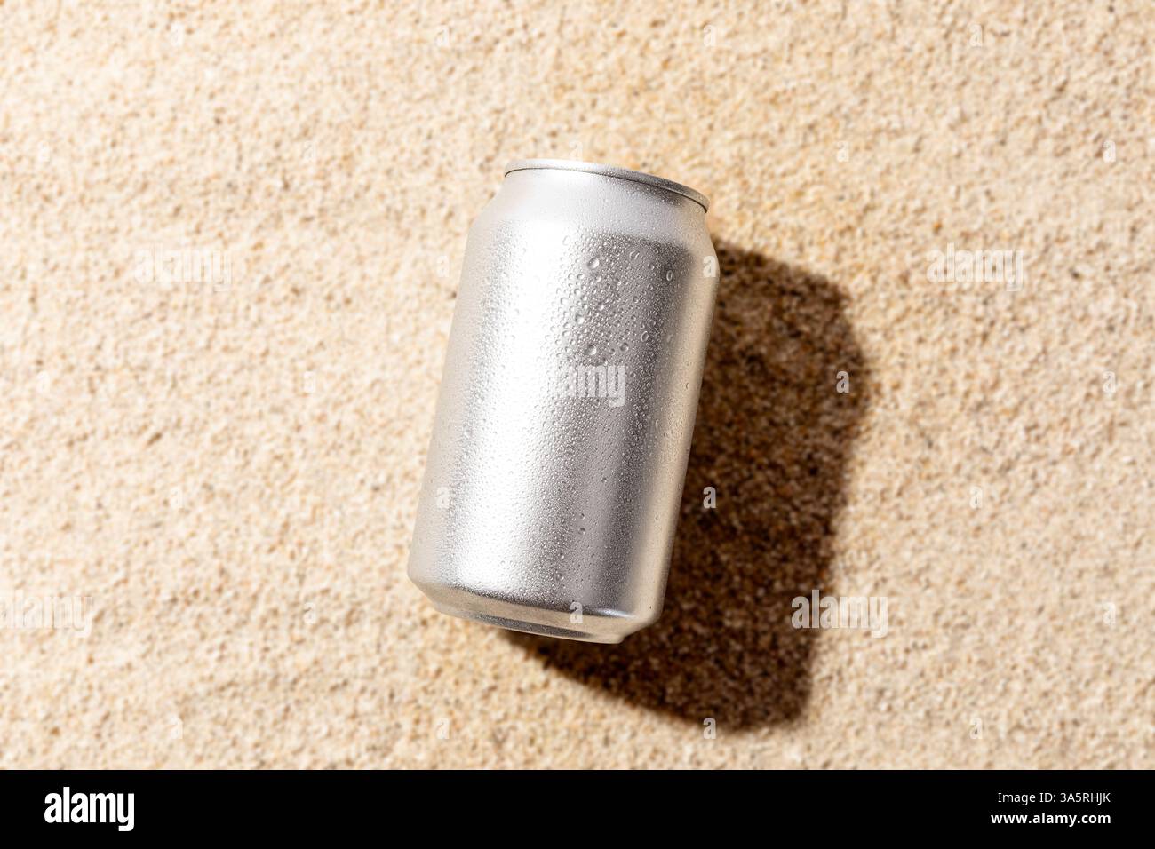 La maquette de soude en aluminium est isolée sur fond de sable de plage Banque D'Images