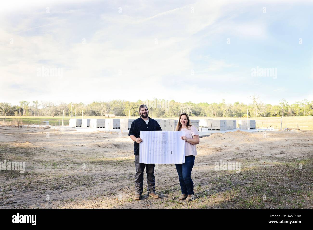 Couple heureux tenant des plans sur leur site de construction à la maison. Banque D'Images
