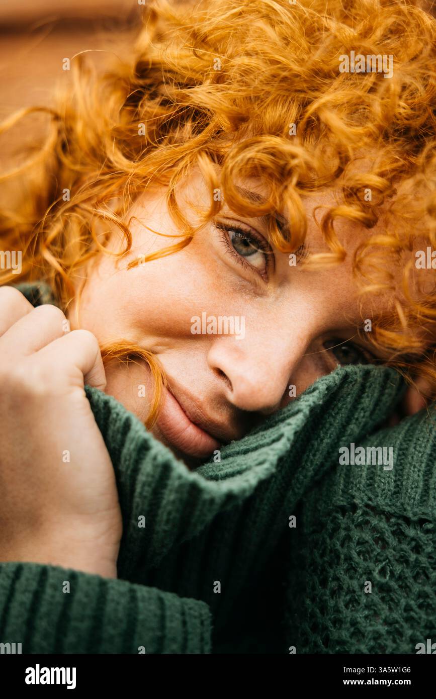 Portrait en gros plan d'une femme rousse souriante se relaxant et tenant son pull vert chaud Banque D'Images Portrait en gros plan d'une femme rousse souriante se relaxant et tenant son pull vert chaud Banque D'Images