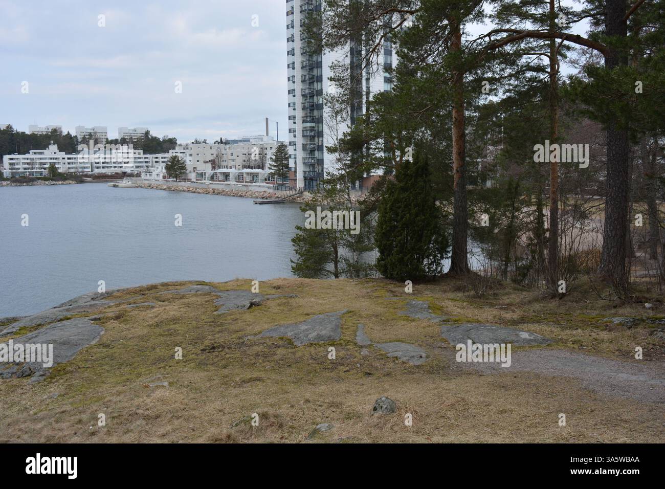 Paysages lumineux et colorés avec une baie et une nature printanière à Espoo, Finlande. Un grand et large chemin avec de grands pins verts, de grosses pierres. Banque D'Images
