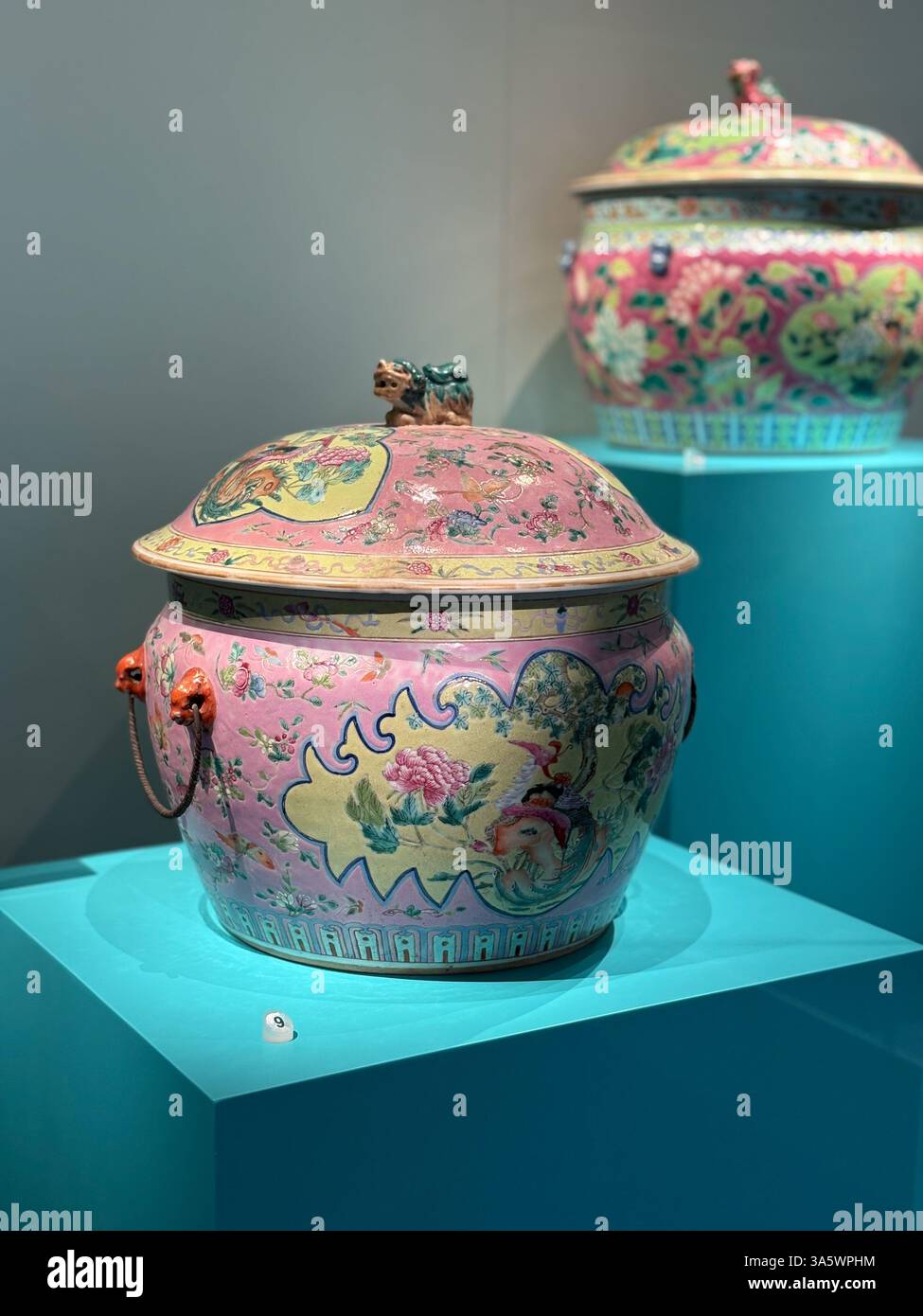 Un gros plan d'un pot nyonyaware de couleur rose avec une couverture. Le pot a des poignées et est décoré de motifs floraux. Banque D'Images